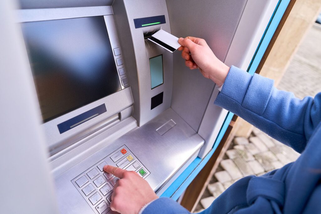 Person insert plastic credit card into atm bank dials pin code keyboard withdrawing money