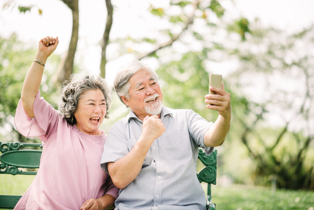 Senior asian couple laughing with smartphone